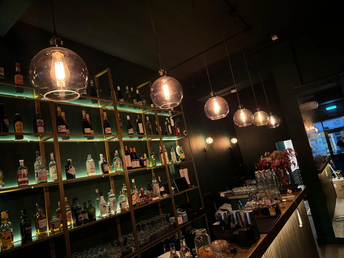 Pendant lights at staggered drops above a lit bottle display