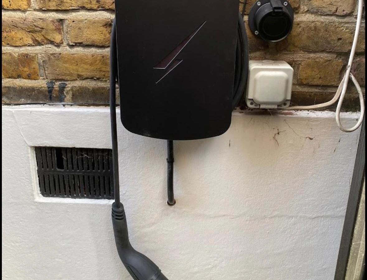 Tethered EV charger and weatherproof socket on an exterior wall