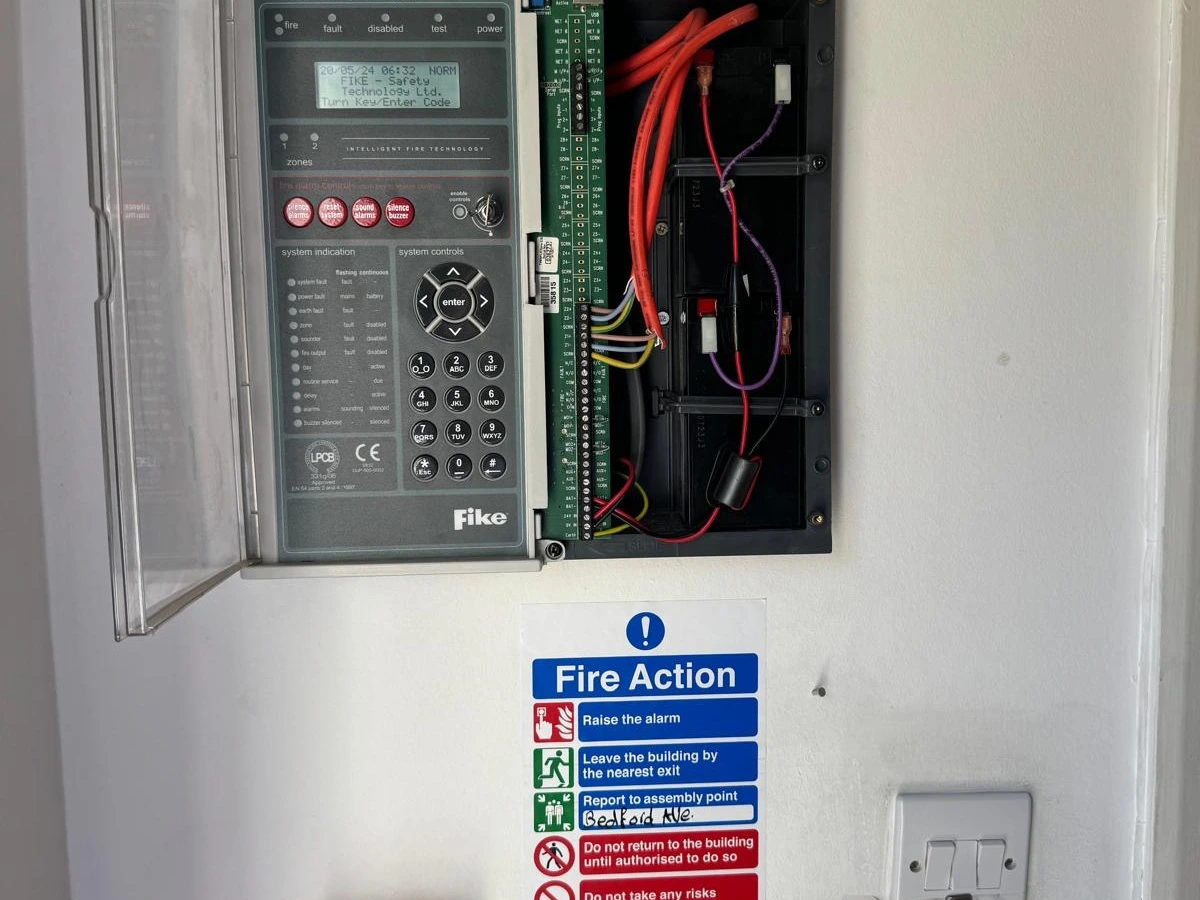 Fire alarm panel wired and open beside a fire action notice