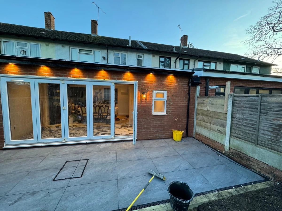 Soffit downlights and a wall lantern lit across a rear extension