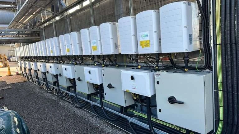 Long row of solar inverters and isolators on a commercial site